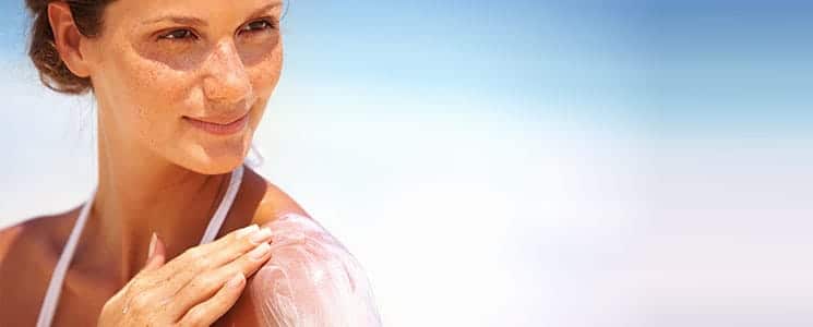 woman applying sun tan lotion on shoulder