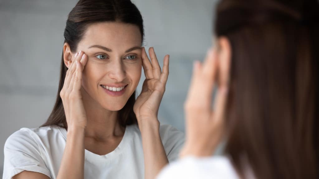 woman with smile lines pulling her eyes up in the mirror