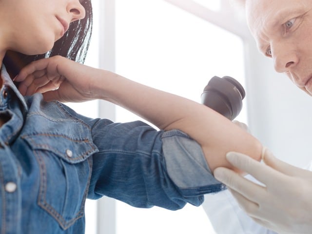 senior doctor using dermatoscope for skin examination at work