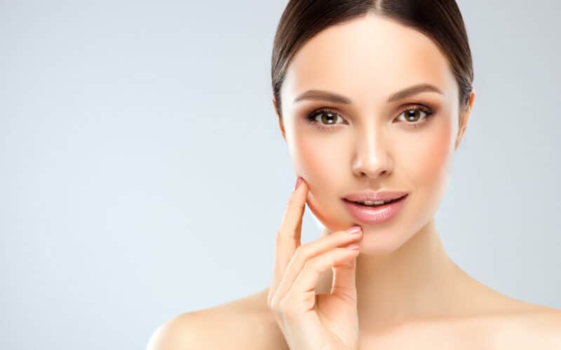 A woman touching her cheek after getting JUVÉDERM® for Smile Lines